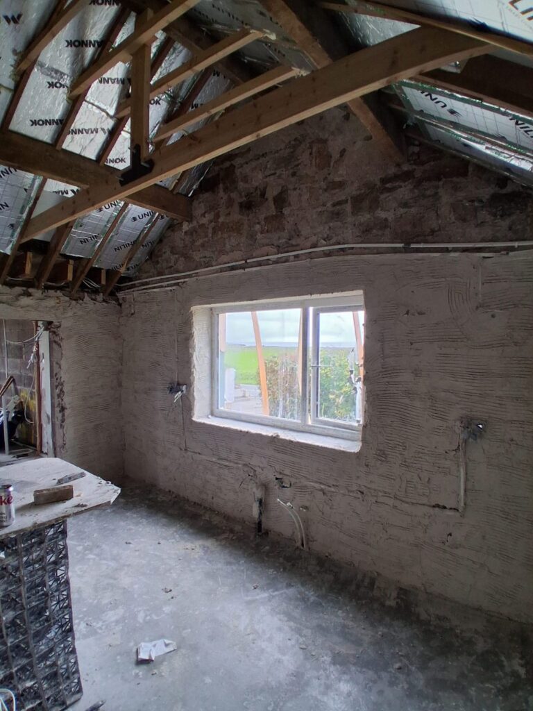 Scratch coat on old stone walls in a cottage renovation