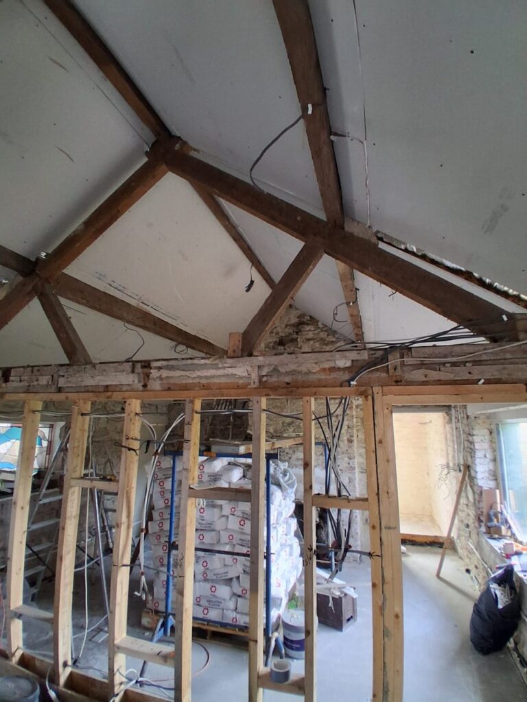 Old roof trusses and new stud wall in a stone building renovation